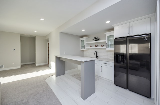 kitchen with open shelves, white cabinetry, stainless steel fridge with ice dispenser, and a sink