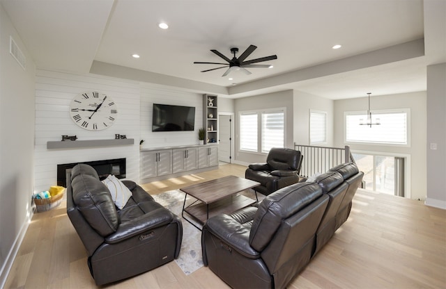 5015 149th Ct, Urbandale, IA 50323 - living area with a ceiling fan, light wood-style flooring, recessed lighting, a tray ceiling, and a large fireplace