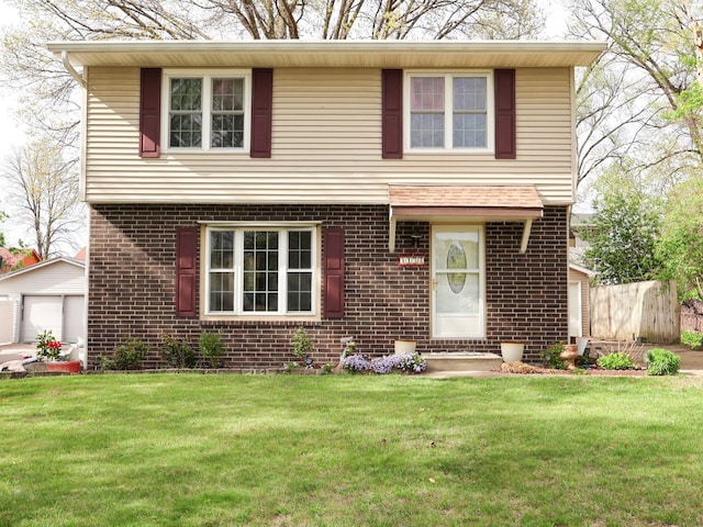 view of front of house with fence, a front lawn, brick siding, a detached garage, and an outbuilding