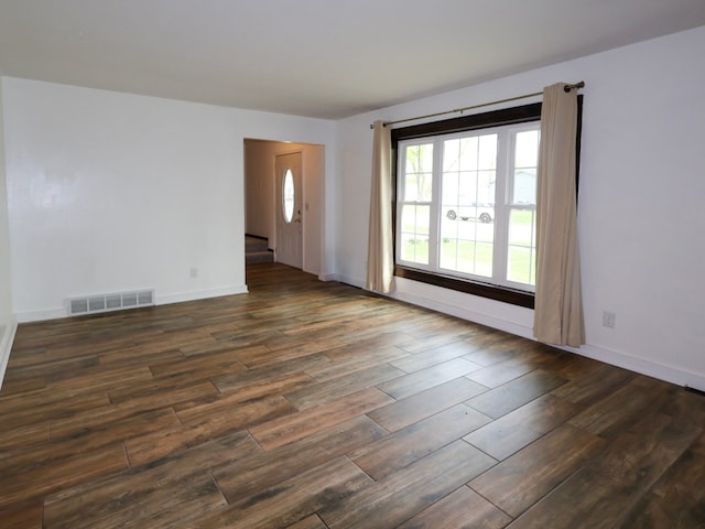 spare room featuring visible vents, dark wood-style flooring, and baseboards