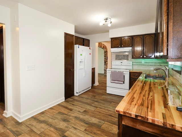 kitchen with arched walkways, dark brown cabinets, a sink, under cabinet range hood, and white appliances
