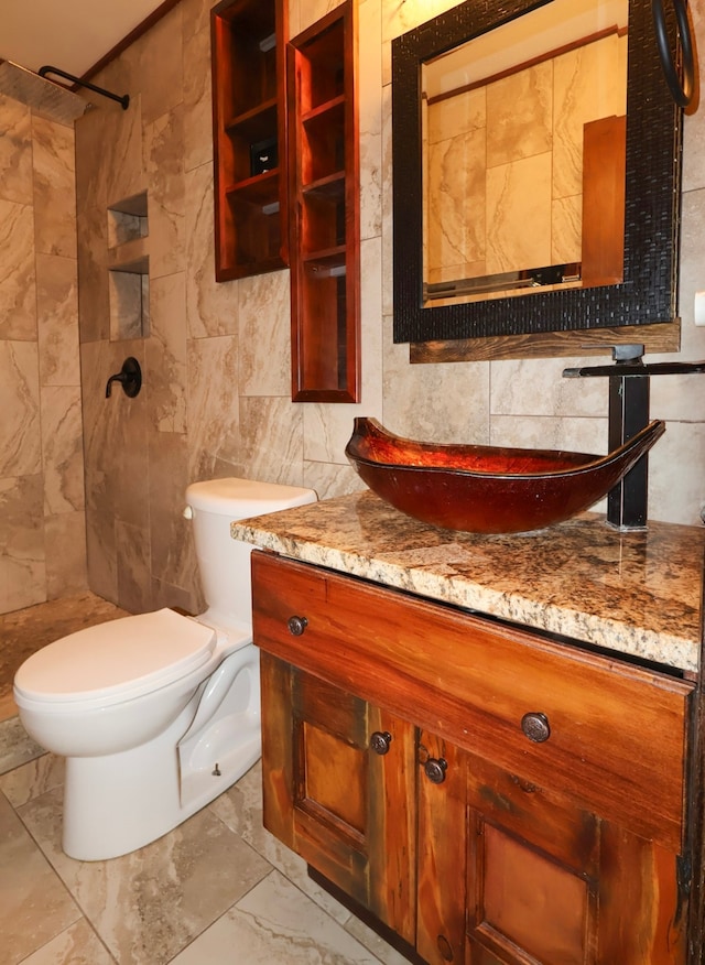 full bathroom featuring vanity, marble finish floor, a tile shower, and tile walls