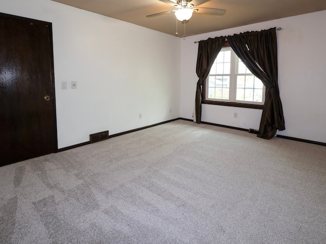 spare room featuring a ceiling fan, baseboards, visible vents, and light carpet