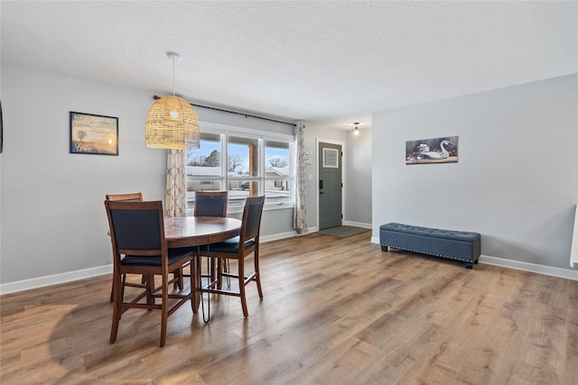 dining space featuring wood finished floors, baseboards, and a textured ceiling