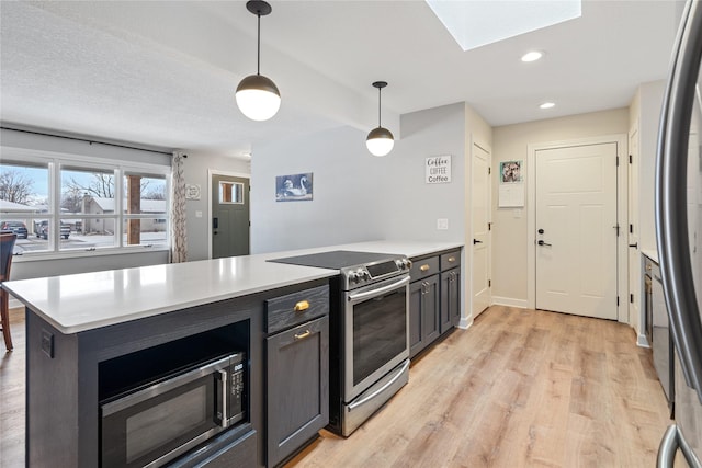 kitchen with light wood finished floors, appliances with stainless steel finishes, a skylight, and light countertops