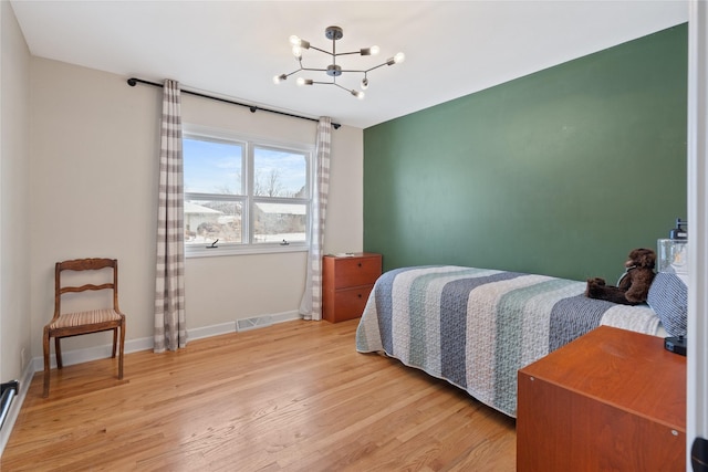 bedroom featuring visible vents, baseboards, a chandelier, and light wood finished floors