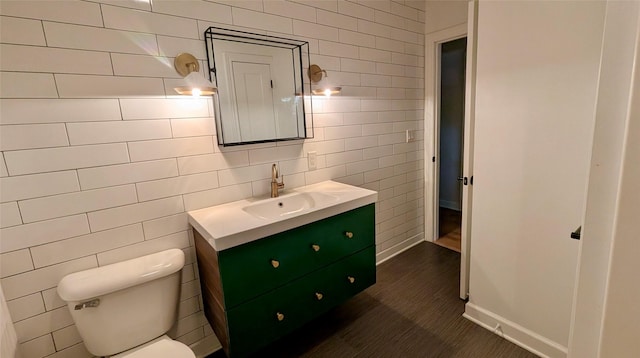 bathroom featuring vanity, tile walls, toilet, and baseboards