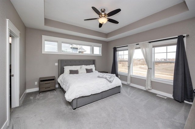 bedroom featuring a tray ceiling, visible vents, baseboards, and carpet flooring