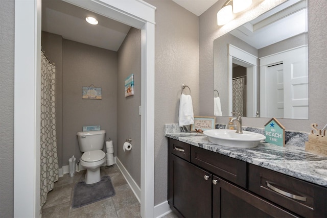 bathroom featuring baseboards, toilet, vanity, and a textured wall