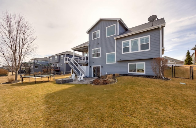 back of property featuring a trampoline, fence, stairway, a yard, and a gate