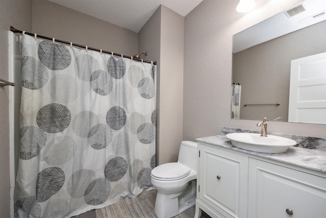 full bathroom with a shower with curtain, toilet, vanity, and a textured wall