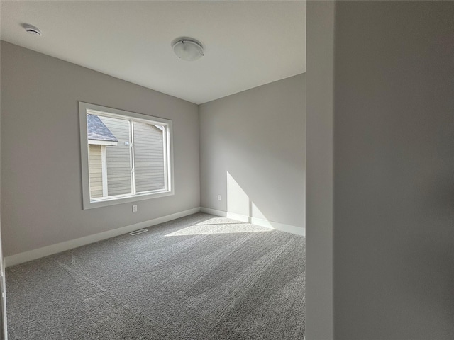 carpeted spare room featuring visible vents and baseboards