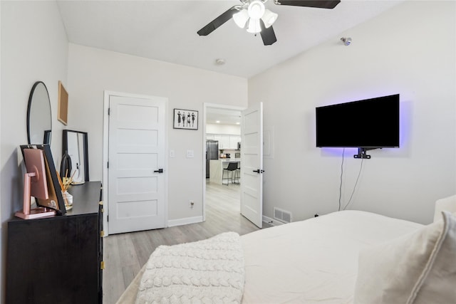 bedroom with visible vents, ceiling fan, baseboards, wood finished floors, and stainless steel fridge