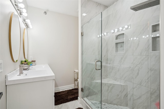 full bath featuring baseboards, vanity, and a shower stall