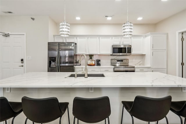 kitchen with a sink, stainless steel appliances, visible vents, and decorative backsplash