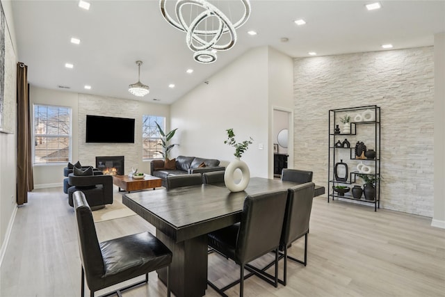 dining room featuring a chandelier, recessed lighting, a fireplace, and light wood-style floors