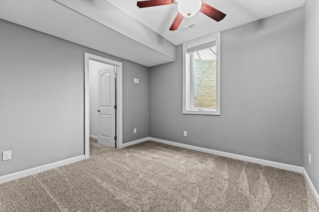 carpeted empty room with visible vents, baseboards, a textured ceiling, and ceiling fan