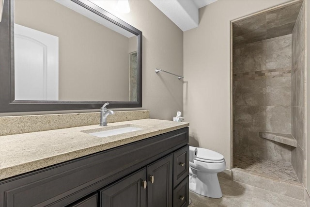 bathroom featuring tile patterned floors, toilet, vanity, and a tile shower