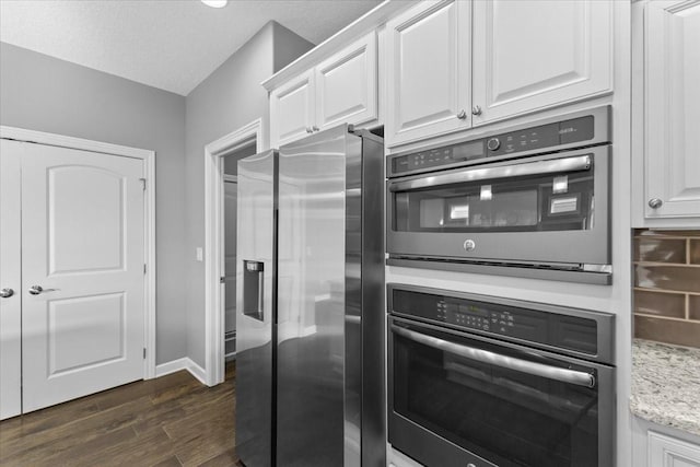 kitchen featuring baseboards, light stone countertops, dark wood finished floors, appliances with stainless steel finishes, and white cabinets