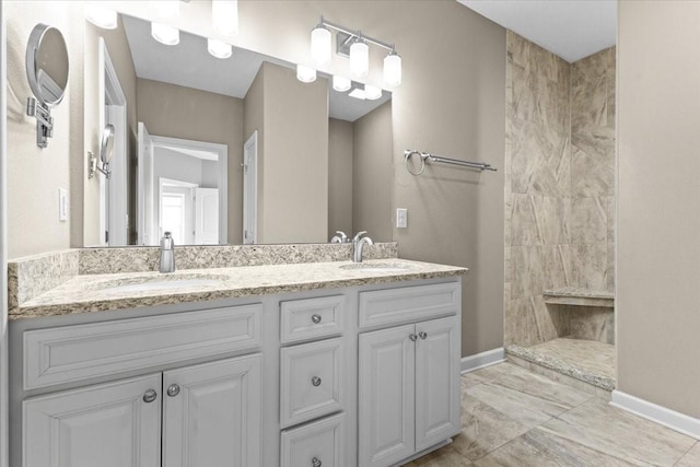 bathroom featuring double vanity, baseboards, walk in shower, and a sink