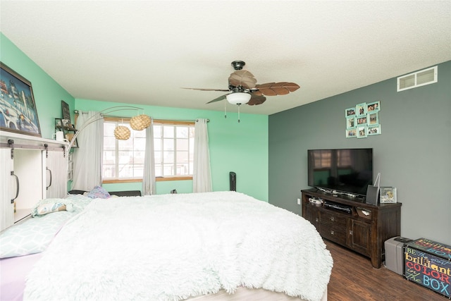 bedroom featuring a textured ceiling, wood finished floors, visible vents, and ceiling fan