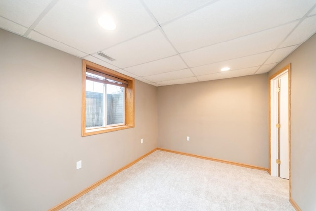 carpeted spare room featuring baseboards, visible vents, and a drop ceiling