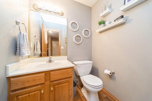 half bath with vanity, toilet, wood finished floors, and baseboards