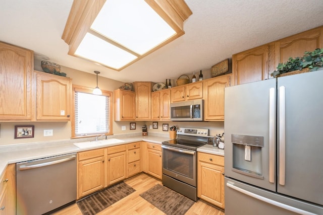 kitchen featuring a sink, light brown cabinets, light wood finished floors, and stainless steel appliances