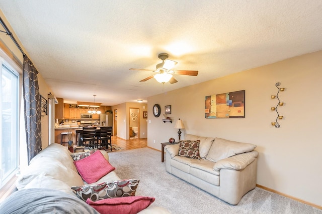 living room featuring light carpet, a textured ceiling, and ceiling fan