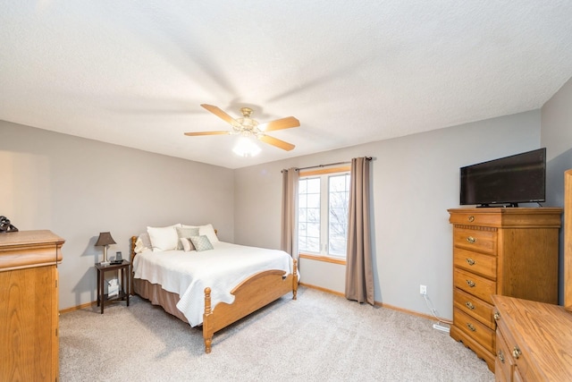 bedroom featuring light colored carpet, baseboards, and a textured ceiling