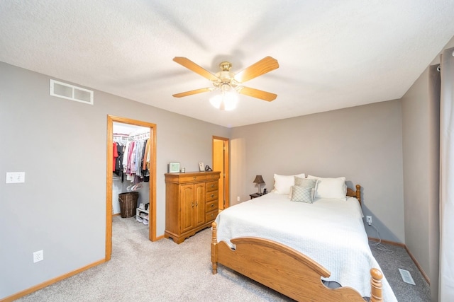 bedroom with a spacious closet, visible vents, light carpet, and baseboards