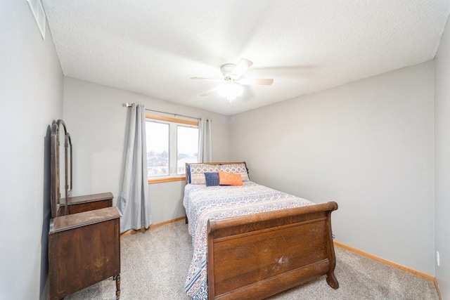 bedroom with light colored carpet, baseboards, and a textured ceiling