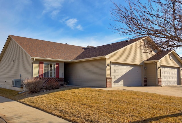 ranch-style house with brick siding, a shingled roof, a front yard, cooling unit, and a garage