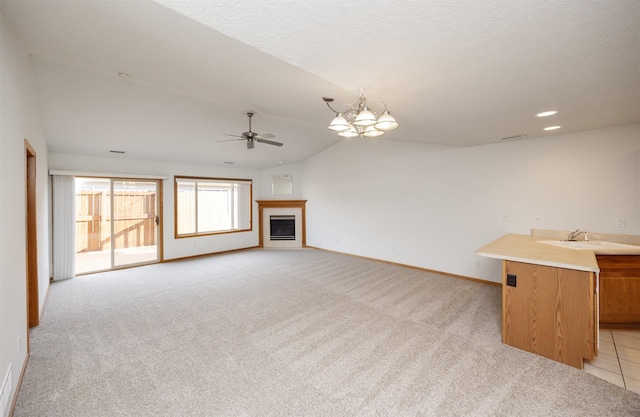 unfurnished living room featuring baseboards, a fireplace, a sink, vaulted ceiling, and light carpet