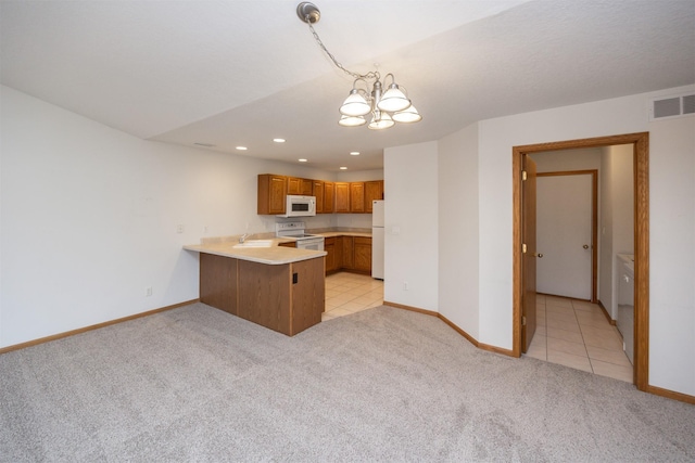 kitchen featuring visible vents, light carpet, a peninsula, brown cabinetry, and white appliances