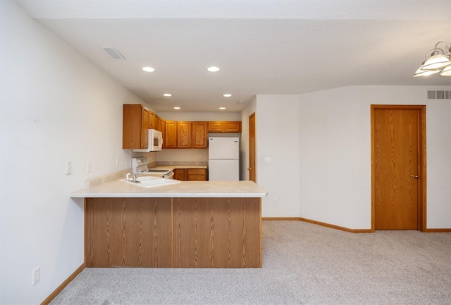 kitchen with visible vents, white appliances, a peninsula, and light countertops