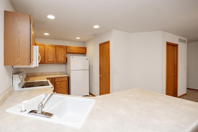 kitchen with visible vents, light countertops, recessed lighting, white appliances, and a sink