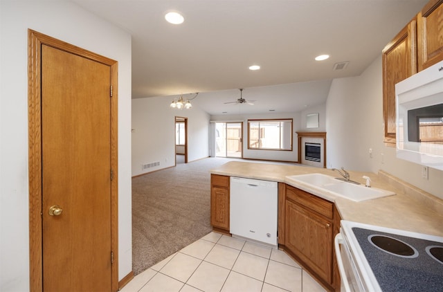 kitchen featuring white appliances, visible vents, a sink, a glass covered fireplace, and light colored carpet