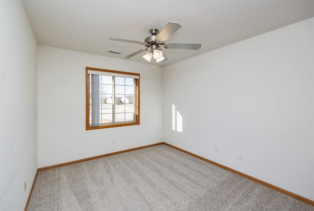 empty room featuring baseboards, visible vents, carpet floors, ceiling fan, and a textured ceiling