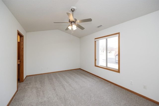 empty room with visible vents, baseboards, light colored carpet, lofted ceiling, and a ceiling fan