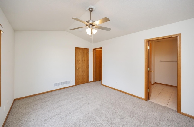 spare room with baseboards, visible vents, lofted ceiling, ceiling fan, and carpet flooring