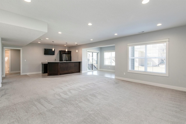 unfurnished living room with recessed lighting, baseboards, and light carpet