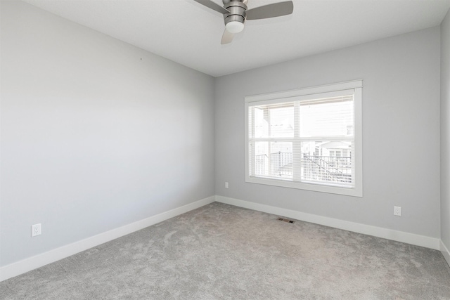 carpeted spare room featuring visible vents, ceiling fan, and baseboards