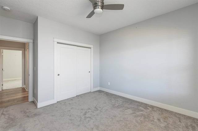 unfurnished bedroom featuring baseboards, carpet floors, ceiling fan, a closet, and a textured ceiling