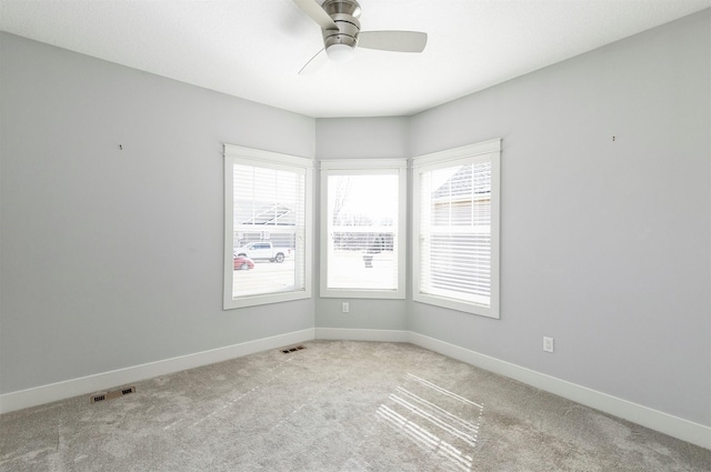 carpeted spare room with visible vents, ceiling fan, and baseboards