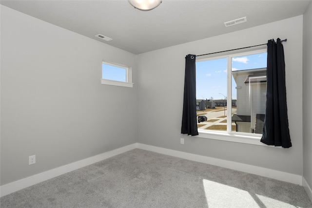 spare room featuring visible vents, baseboards, and carpet