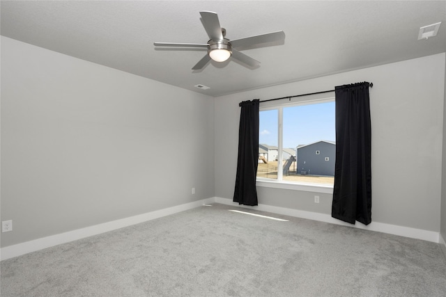 carpeted spare room with visible vents, baseboards, and a ceiling fan