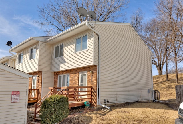 back of property featuring a wooden deck and brick siding