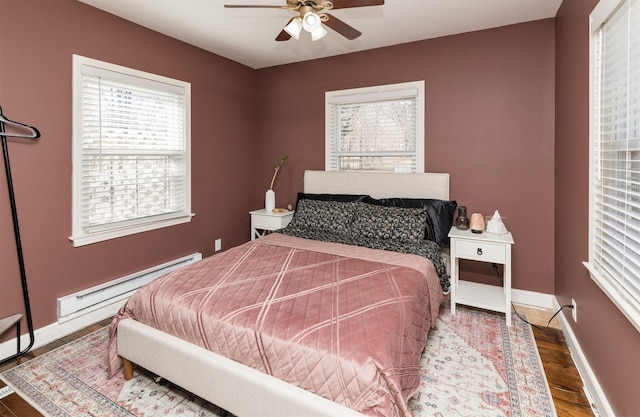 bedroom featuring baseboard heating, baseboards, a ceiling fan, and wood finished floors