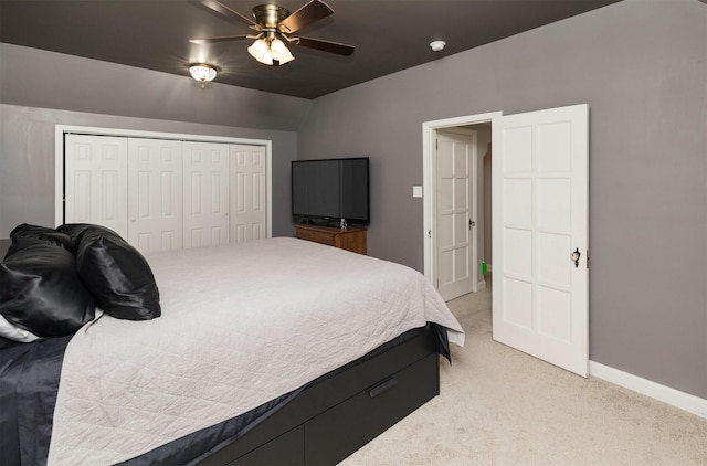 bedroom with light carpet, a ceiling fan, baseboards, and a closet